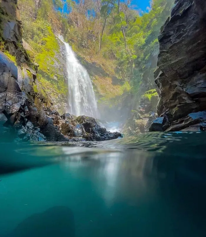 Catarata que cae entre paredes de roca a una poza turquesa