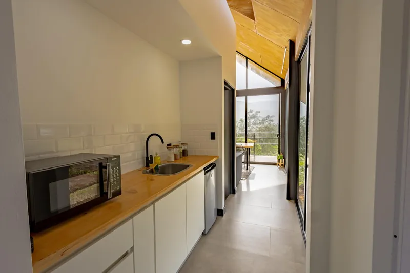 Cocina con microondas, fregadero y refrigerador, y el pasillo hacia la terraza