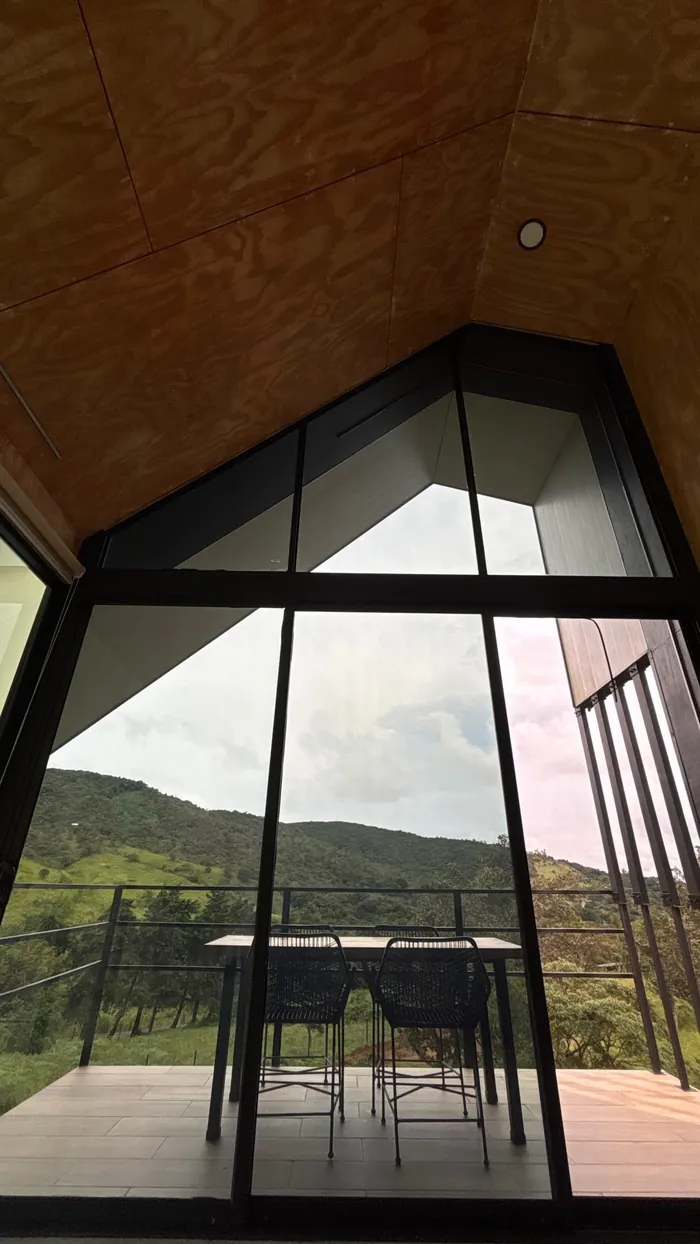 Ventanal en forma de casa con la mesa de la terraza y las montañas