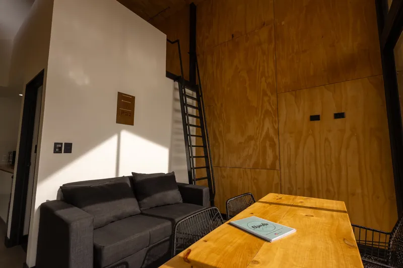 Sala con sofá gris, mesa de madera y la escalera al mezzanine